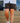 Model wearing the Daydrift shorts walking down stairs with a deck & house in the background