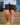 Model wearing the Daydrift shorts walking down stairs with a deck & house in the background