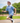 Model wearing the Flightless Boy's polo running around on a playground with greenery in the background