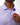 An angled close up of the buttons on the Lavender Haze Jacquard Polo. There is a piece of fabric that hides the buttons, which the model is pulling open. The polo is featured on a model in front of a white background.