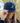 A female model wearing the True Blue Flight hat outside with greenery in the background