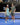 Man and woman in workout attire holding a pickleball and paddles