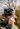 A man outdoors wearing a camo Repel hat with a bright orange antler graphic on the front, paired with a matching camouflage jacket.
