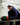 Brock Faber wearing a navy blue hoodie, a white and blue hat, and a navy sweat set, leaning on ice rink boards.