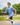 Model wearing the Flightless Boy's polo running around on a playground with greenery in the background