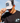 Model wearing the Galactic Greens Trucker Hat doing a hat tilt with blue sky as the background