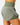 Close up on the Waggle "W" perforation on the back of the Hunter Green Momentum Shorts on a model in front of a light gray background.