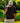 Model wearing the Longtail Polo on the golf course leaning against a fence, with greenery in the background.