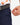 Close up on the Zippered pocket on the left leg of the Navy Ace Pants on a model in front of a white background