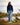 Model wearing the Navy Plume Funnel neck outside walking down a dirt path with a lake and trees in the background.