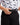 Model putting a belt through the belt loops on the Boy's Scramble Short on a model in front of a light gray background.