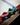 Three pom-pom beanies are lined up on a red boards edge at an ice rink.