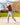 Model wearing the Rack Star Polo on the course hitting out of a bunker, with trees and fairway in the background.