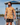Male Model wearing the Raked Camp Shirt walking down a dock on a lake with blue skys in the background