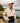 Model wearing the Sandstone Surge Pullover outside on a shoreline of a lake with water and trees in the background.