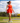 Model wearing the Scarlet Crossover Tank on the golf course with greenery and ultra blue sky's in the background