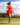 Model wearing the Scarlet Crossover Tank on the golf course with greenery and ultra blue sky's in the background