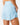Close up on the Waggle "W" perforation on the back of the Sky Blue Momentum Shorts on a model in front of a light gray background.