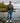Male model wearing the Squatch Wildknit Sweater outside standing on a shoreline with a lake and trees in the background.