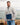 Model wearing the Superior Surge Pullover outside on a rocky shoreline with a lake and sky in the background.