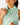 Close up on the collar of the Real Dill Sleeveless Polo on a model in front of a light gray background.