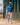 Model wearing the Upstream Habitat Polo walking down a city sidewalk with buildings in the background.