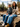 Man and woman sitting next to each other in sweaters with a nature landscape behind them.