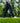 Model wearing the Ace Pants outside with greenery in the background
