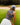 Model wearing the Wildflower Way Sleeveless Polo on the golf course preparing for a shot with a bunker and greenery in the background.